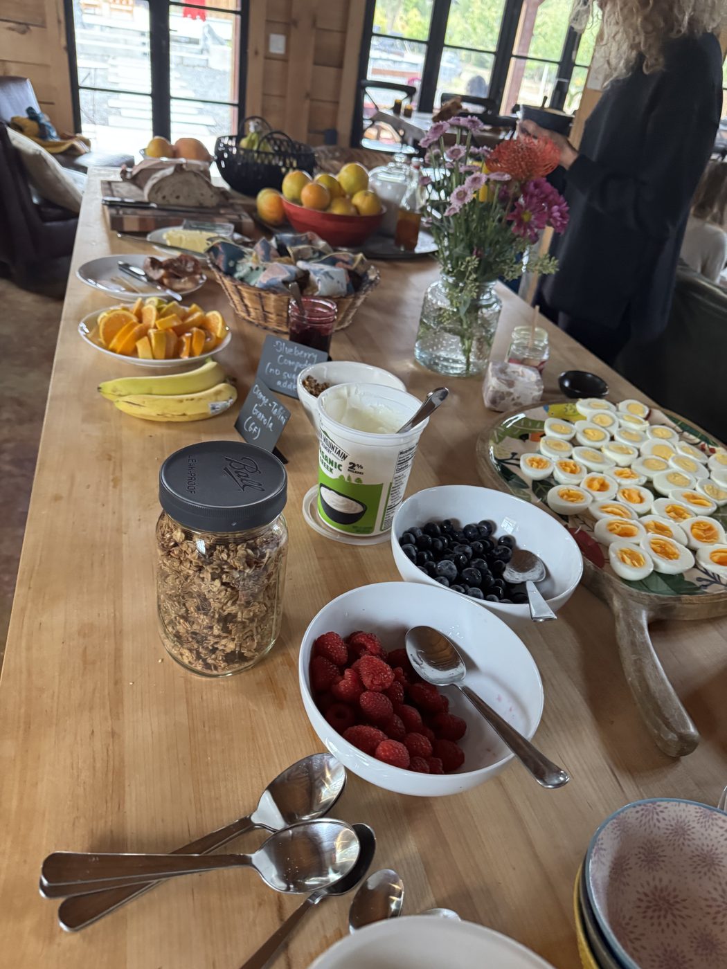 A breakfast bar with granola, yogurt, berries, soft-boiled eggs and flowers.
