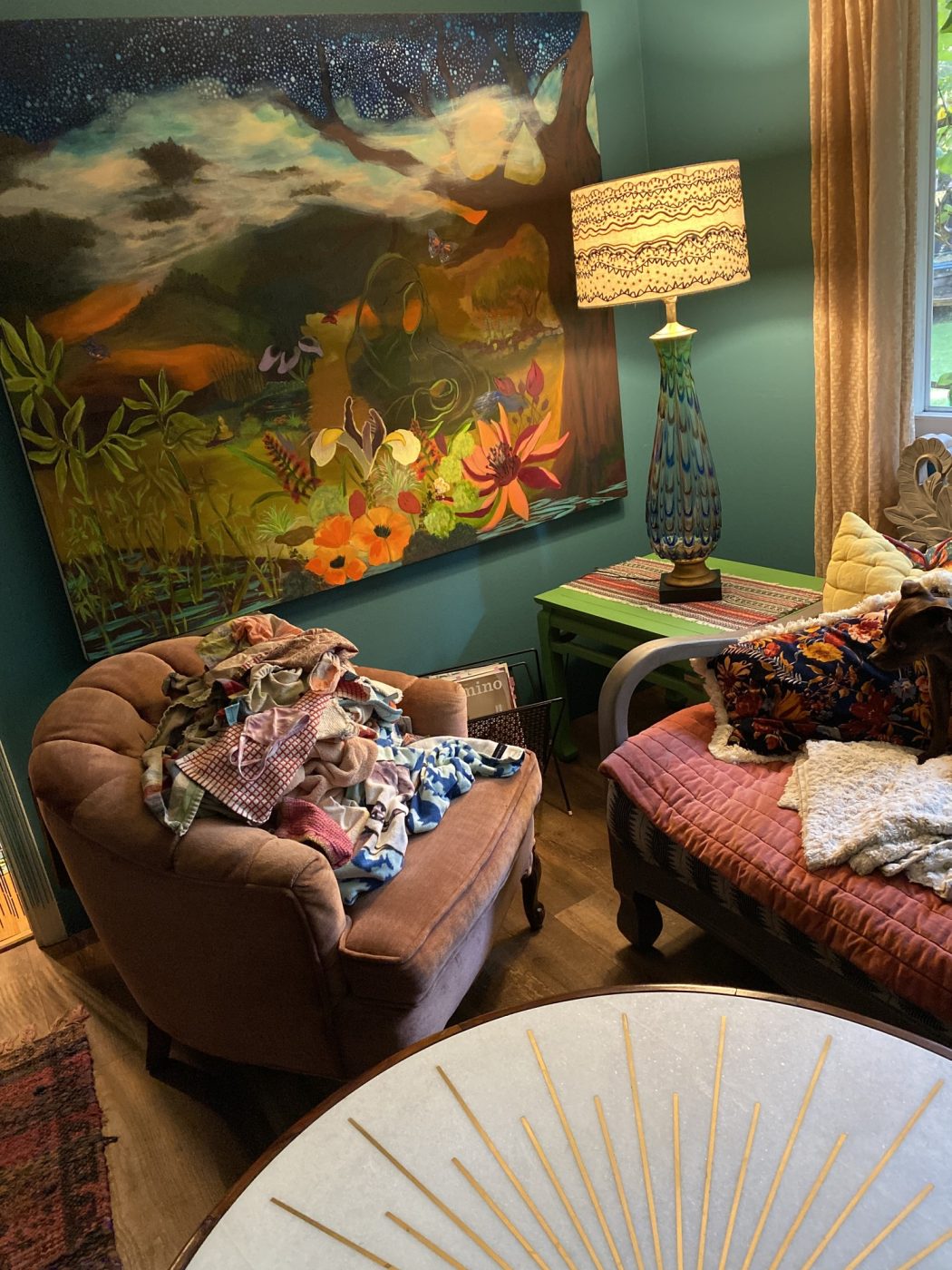 A sunlit sitting room with a lily painting above vintage sofas.